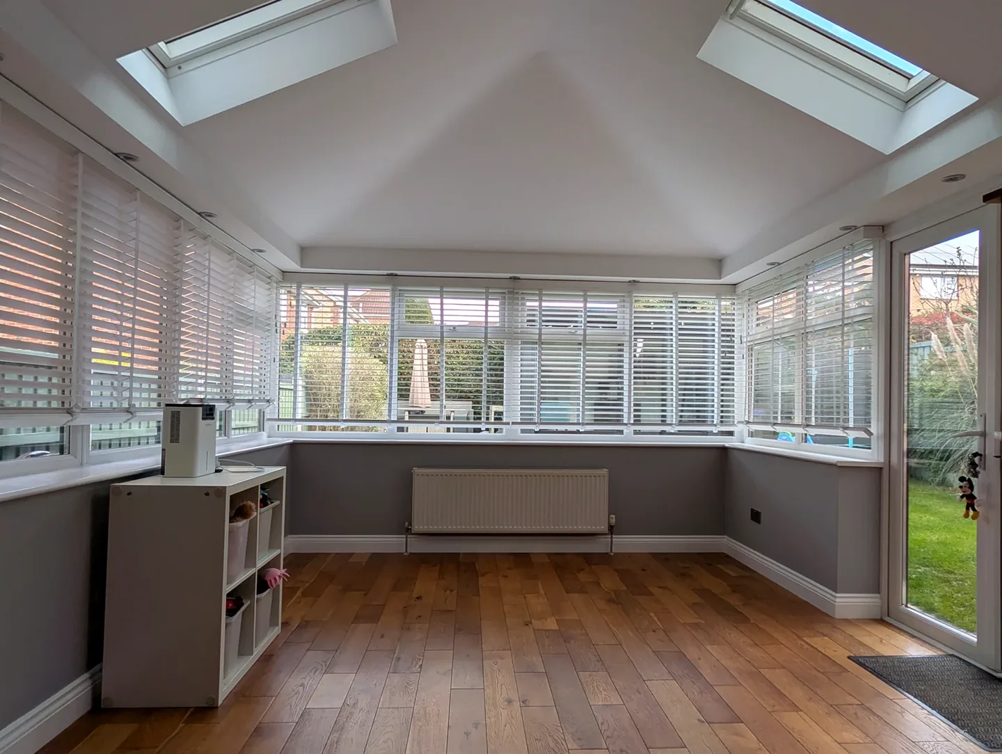 Bright sunroom with grey lower walls, white vaulted ceiling and rooflights